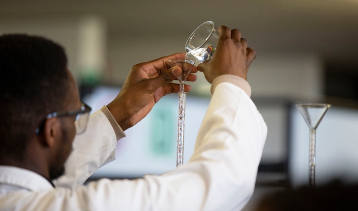 Man in lab pouring liquid
