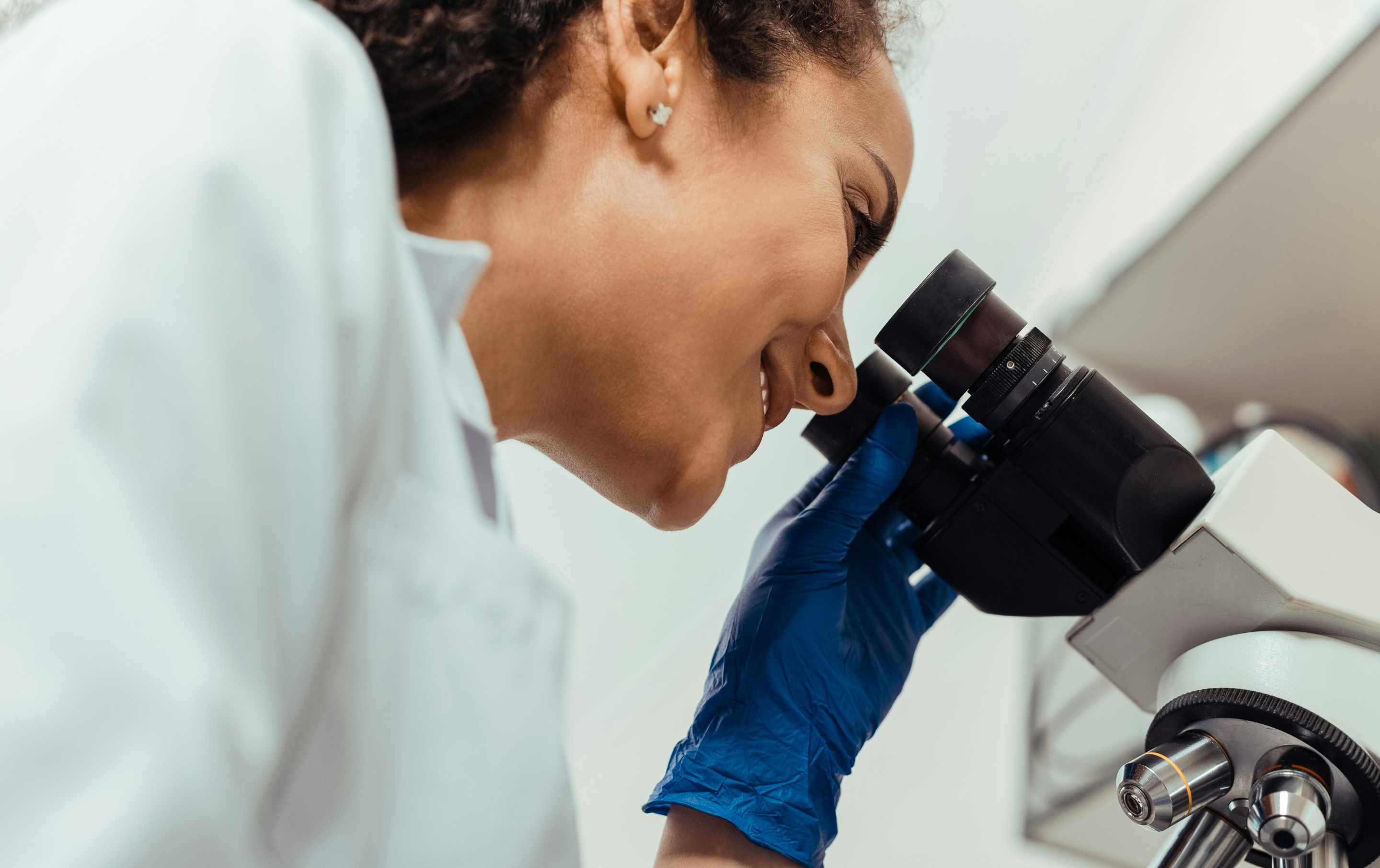 Technician looking at microscope and smiling